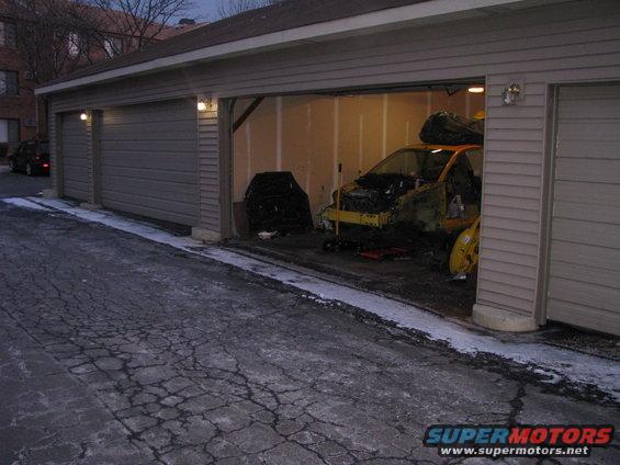 Yellow car in garage, hood open, undergoing tear down