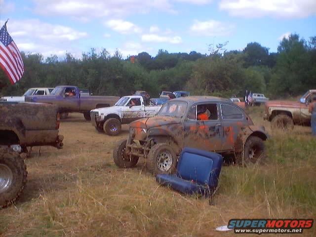 Mud-covered Volkswagen Beetle with off-road tires and orange accents