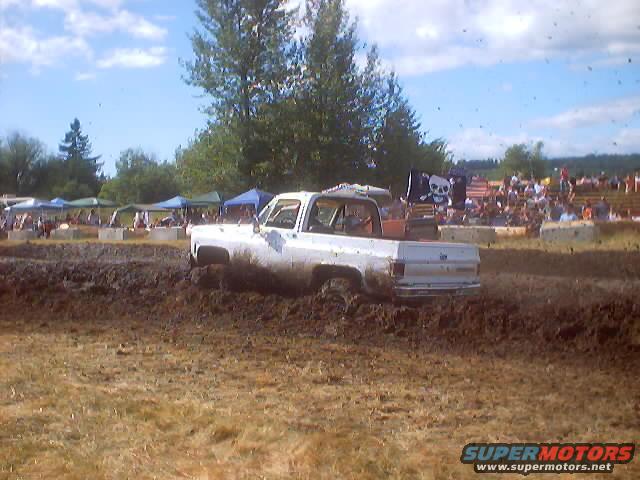 White pickup truck in mud, pirate flag on back
