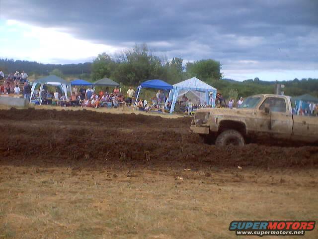 Mud-covered pickup truck stuck in mud at a drag race event