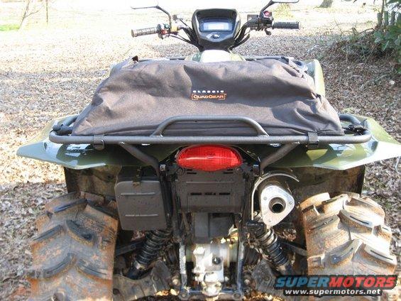 Green ATV rear view with black soft rack bag and large knobby tires