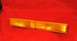 1989 Ford Bronco II - Amber turn signal lens with vertical fluting and a clear end section, on a red textured surface.