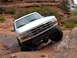 1993 Ford Bronco - White 1993 Ford Bronco navigating a difficult off-road obstacle.