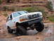 1993 Ford Bronco - This lifted Ford Bronco navigates a rocky desert terrain with steep canyon walls in the background.