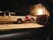 2003 Ford Crown Victoria - A tow truck is seen towing a damaged white car on a snowy road at night.