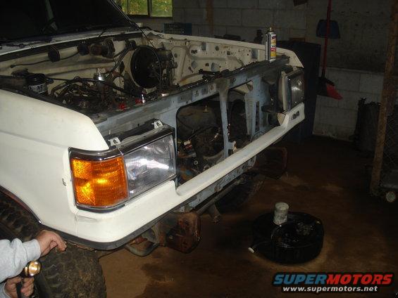 White 1991 Ford Bronco front end with hood open, engine exposed, in a garage.