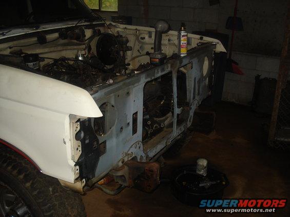 Disassembled white 1991 Ford Bronco front end in a garage with tools.