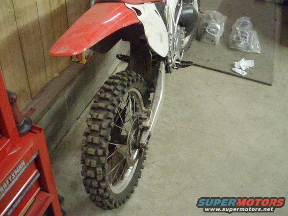 Motorcycle rear wheel and red fender. Craftsman tool chest visible