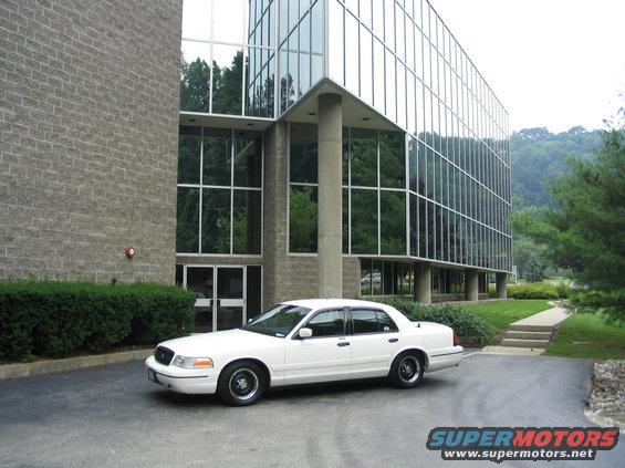White 1998 Ford Crown Victoria parked in front of a modern glass building