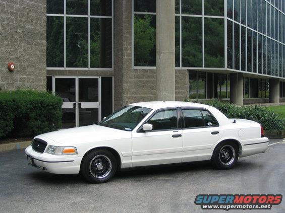 White 1998 Ford Crown Victoria sedan parked outside a modern building