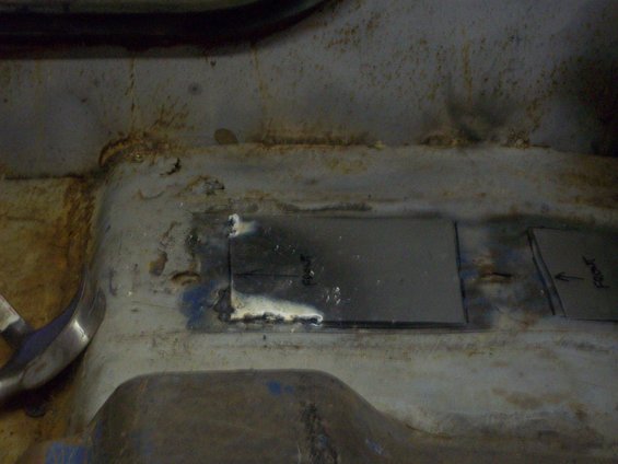 welding patch on rusty vehicle floor pan, with 'Front' written on another patch