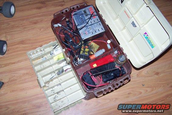 Open tackle box with RC car batteries, charger, and parts