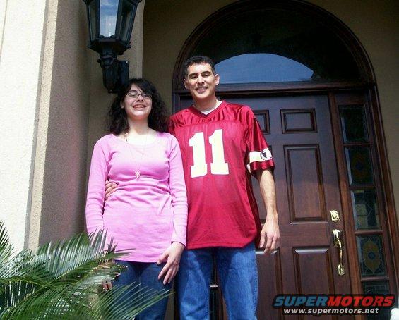 Couple in front of a wooden door with a large arched window above