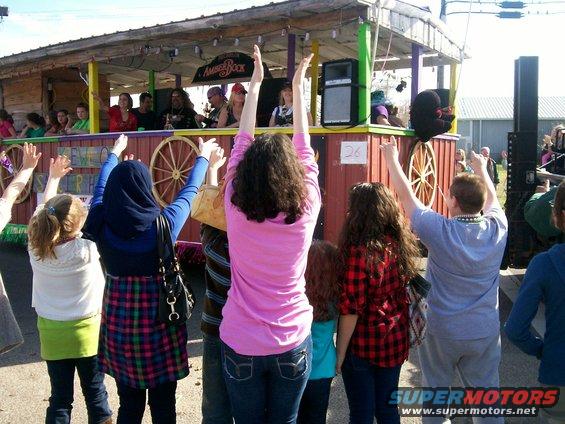 People watching a parade float with a band playing and decorations