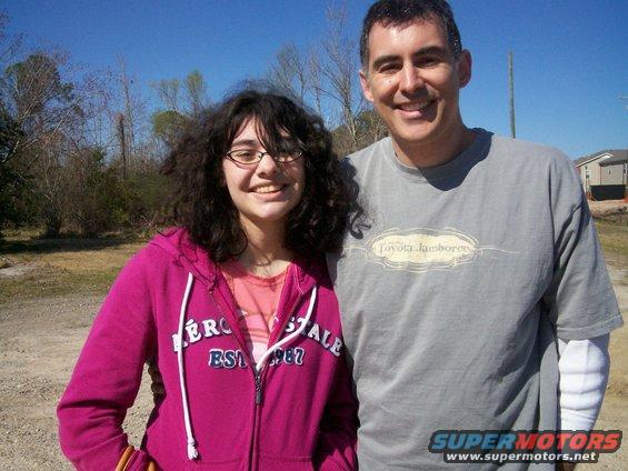 Man and girl smiling outdoors, girl wears pink hoodie, man wears grey t-shirt with Toyota Jamboree logo