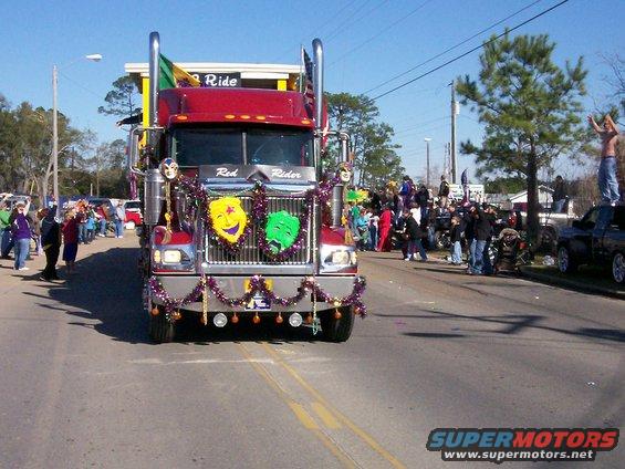 Red semi-truck with Mardi Gras masks and beads