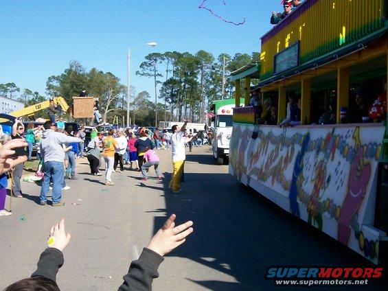 Mardi Gras parade with a decorated float and people watching and throwing beads