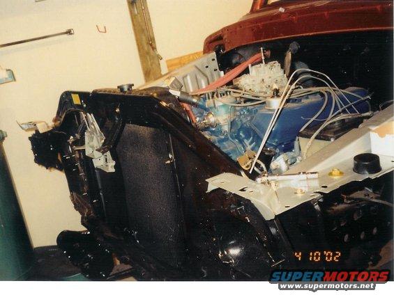 Vehicle engine bay with blue engine block, carburetor, and radiator. Date stamp '4 10 02'