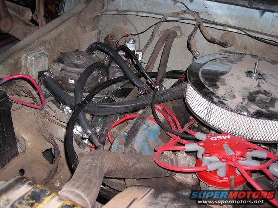 Engine bay with chrome air cleaner, red MSD distributor, and black vacuum hoses. Some rust and dirt visible