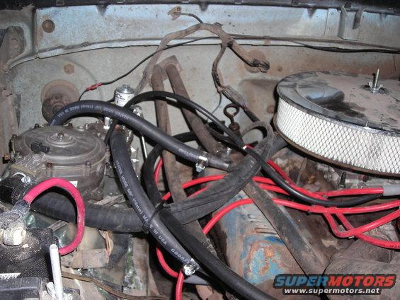 Engine bay showing air filter, carburetor area, and various hoses. Some hoses have 'GOODYEAR' text