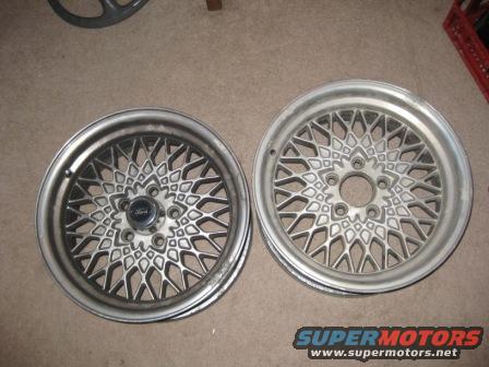 Two silver mesh wheels with Ford center caps, one with visible wear