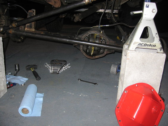 vehicle rear axle differential with tools and a red cover on the ground