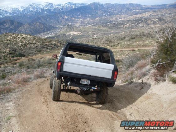 1979 Ford Bronco driving on a dirt trail in the mountains