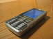 2003 Ford Crown Victoria - A silver Nokia cell phone rests on a wooden table, displaying a blue screen and its numeric keypad.