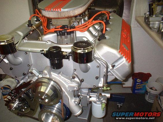 Silver V8 engine with orange spark plug wires and valve covers, chrome pulleys, and an air filter