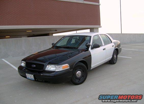 Black and white police car parked on a concrete level of a parking garage. License plate is visible