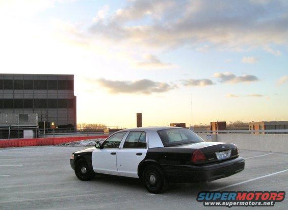Police car parked on a rooftop lot at sunset. Two-tone black and white paint scheme