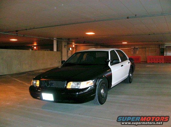 Two-tone police car, black front and white rear, parked in a garage