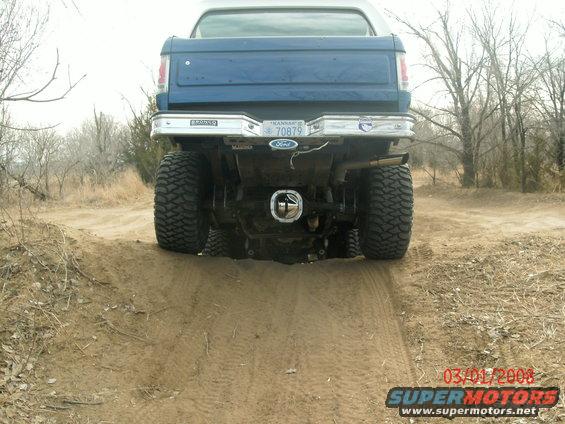 1996 Ford Bronco rear view showing lifted suspension and large tires on a dirt track