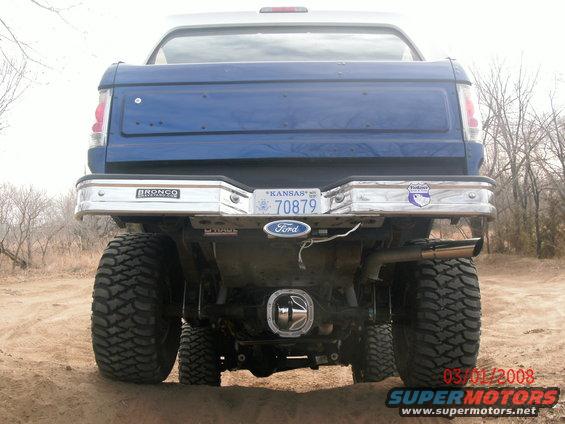 Rear view of a lifted blue Ford Bronco with large tires and a chrome bumper. License plate reads Kansas 70879