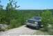 1993 Ford Bronco - A black Ford Bronco is parked on a dirt path surrounded by trees and foliage.