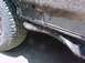 1993 Ford Bronco - The lower body panel and tire of a vehicle are covered in mud and dirt.