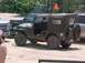 1993 Ford Bronco - A military jeep with a soft top and spare tire is parked next to other vehicles.