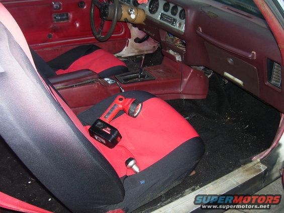 Car interior showing red seats and floor mats. Keys are on a red mat