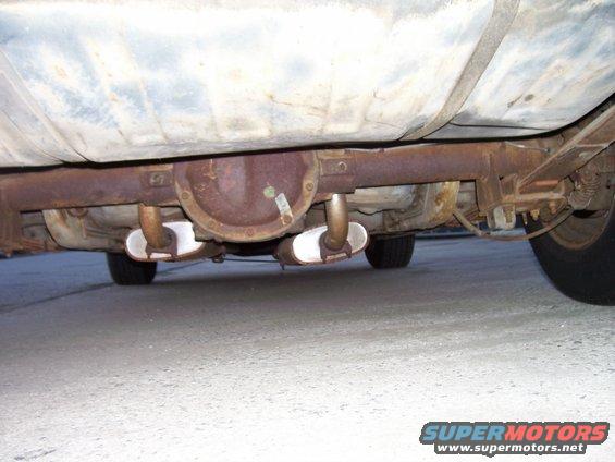 Underside of a car showing the rear differential, exhaust pipes, and fuel tank