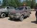 1993 Ford Bronco - Two Ford Broncos are parked on a dirt lot with trees in the background.