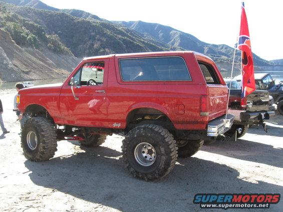 Red 1987 Ford Bronco with lifted suspension and oversized tires parked outdoors