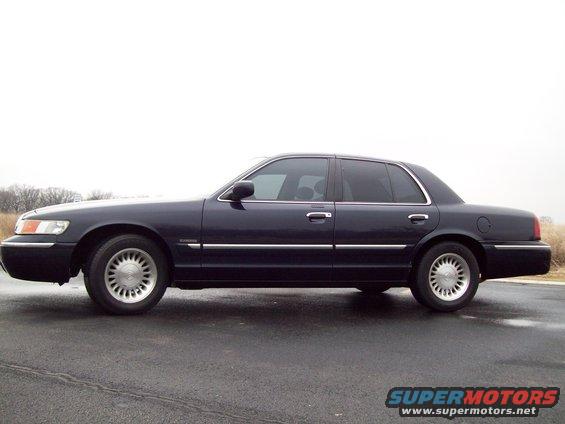 Side view of a 1999 Mercury Grand Marquis parked on a wet road