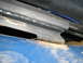 1990 Ford Bronco - A close-up view of a rusted metal frame, possibly from a vehicle's undercarriage, with visible blue paint and wiring.