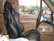 1990 Ford Bronco - Interior view of a car with aftermarket racing seats and a modified steering wheel, with other vehicles seen outside.