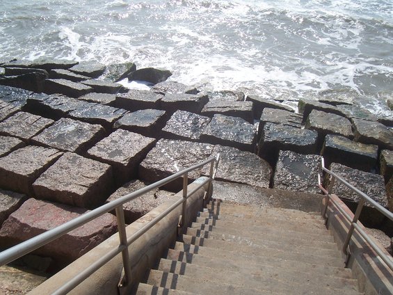 Stone jetty with concrete stairs leading down to the ocean