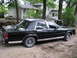 1988 Ford Crown Victoria - A black 1988 Ford Crown Victoria is parked on a dirt lot next to a residential building.