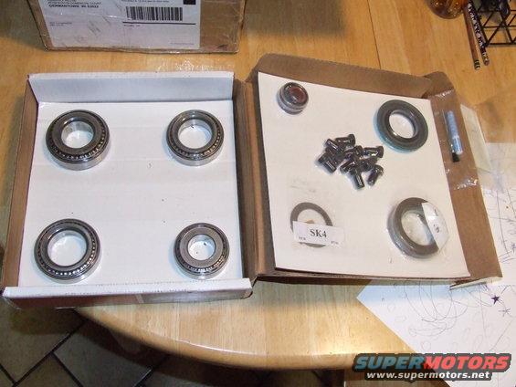 Two boxes of automotive parts: one with four wheel bearings, the other with seals, bolts, and a small tube