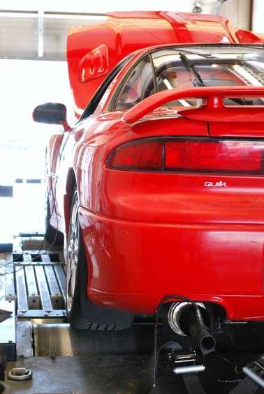 Red 1991 Mitsubishi 3000GT rear on dynamometer rollers, hood open