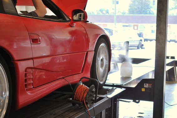 Red 1991 Mitsubishi 3000GT on a dynamometer, hood up, with a person inside