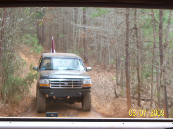 1996 Ford Bronco driving on a wooded dirt road